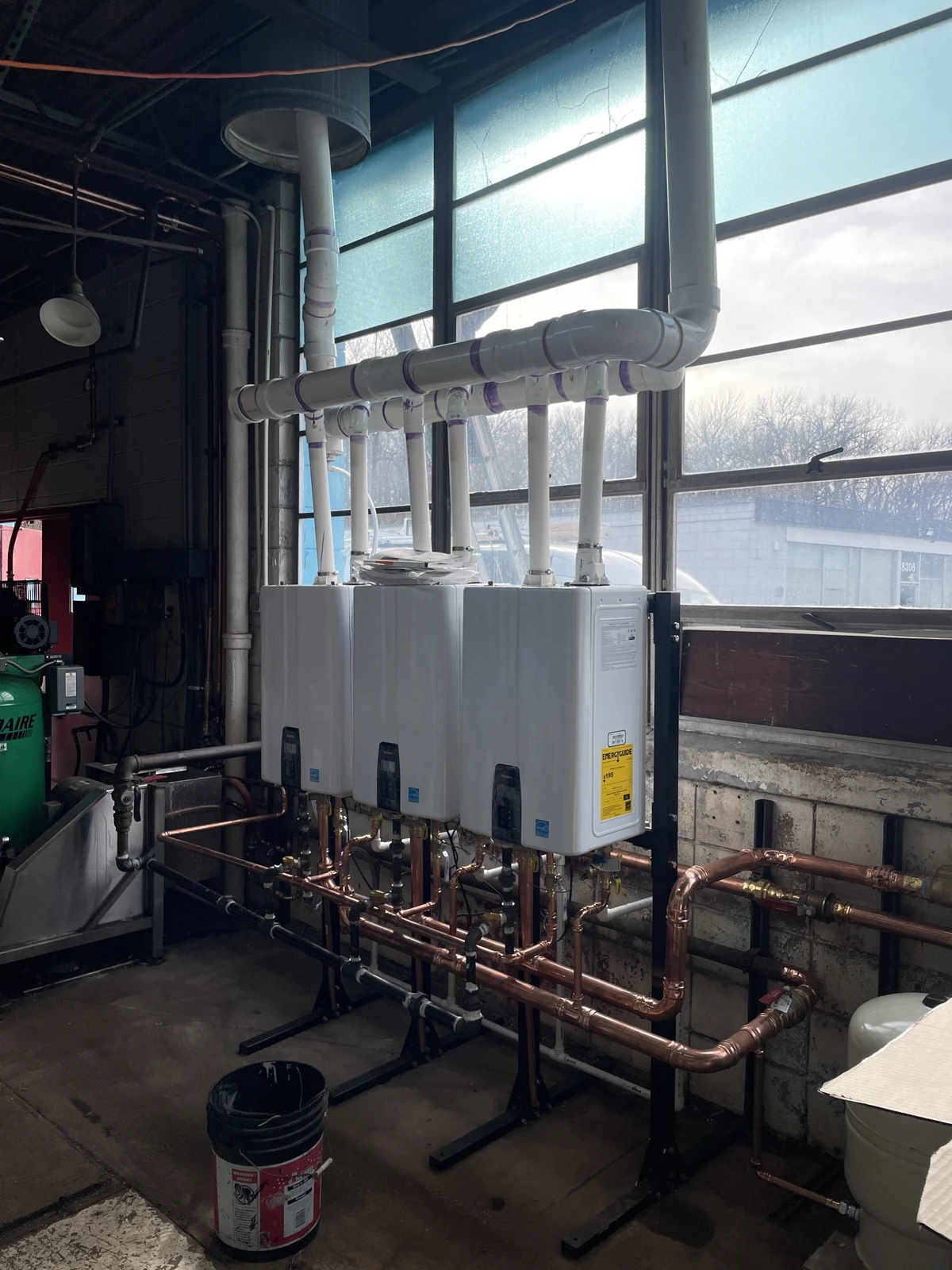 Enclosed mechanical equipment with its front covers in place, copper pipework below and white vent piping above.