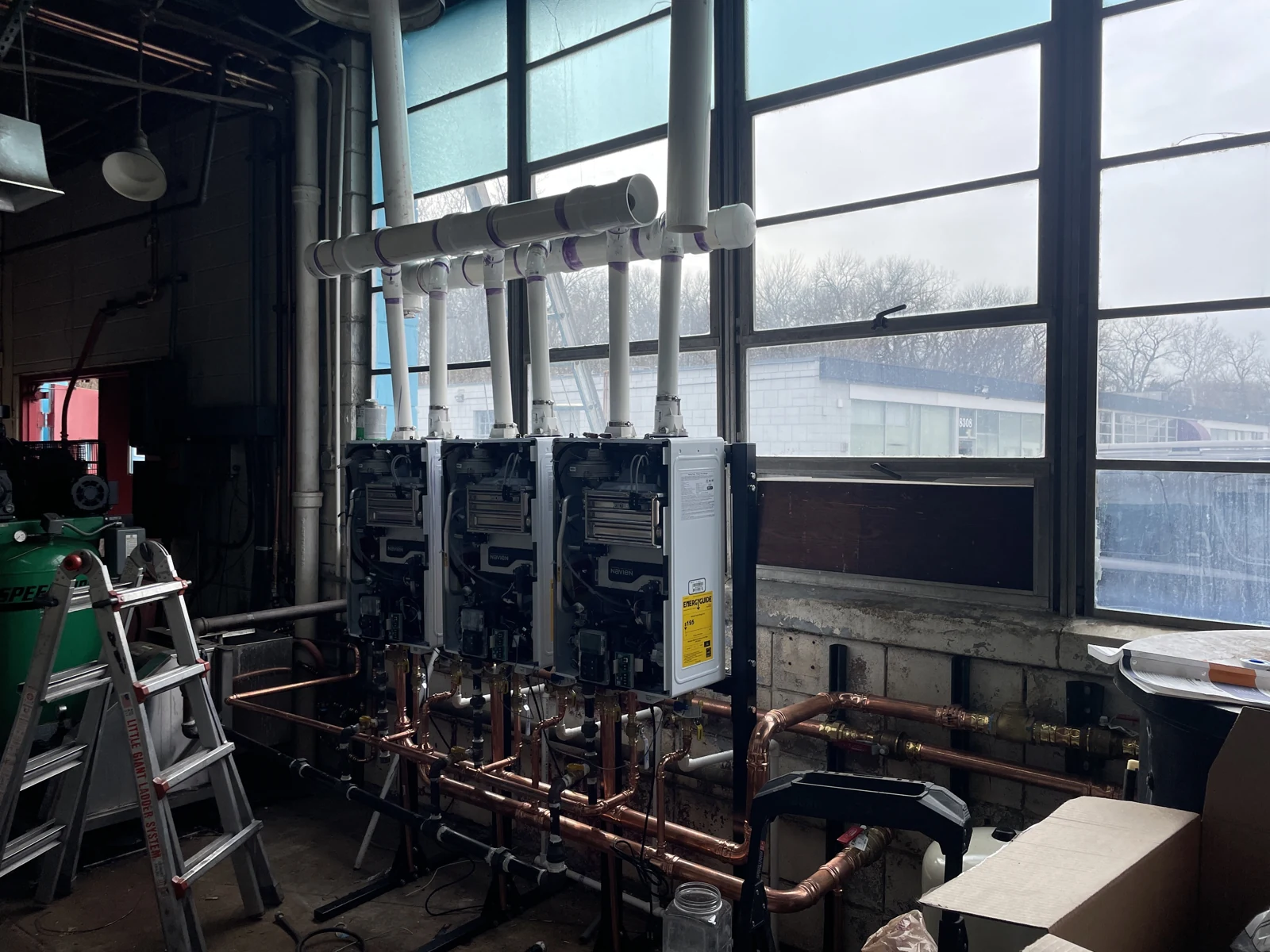 Mechanical equipment with its front panels open, connected copper pipework and overhead venting.